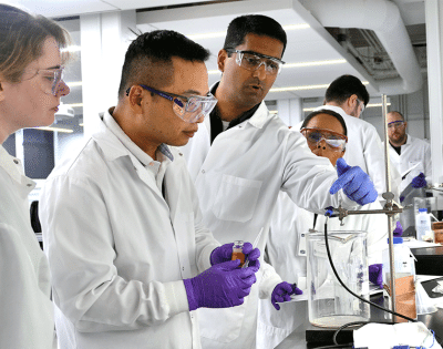 Team of researchers looking through microscope