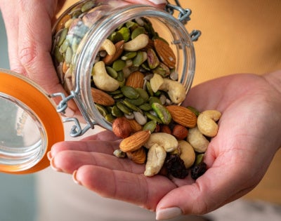 Close up of a person pouring almonds, pistachios and other nuts into their hand