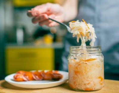 Close-up of a fork with sauerkraut and a piece of Bavarian sausage 