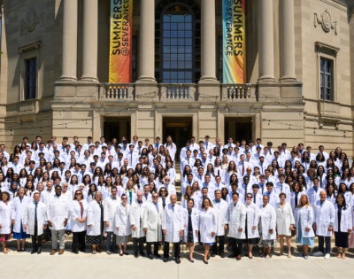 new MD students in their white coats standing all together in front of Severance Hall