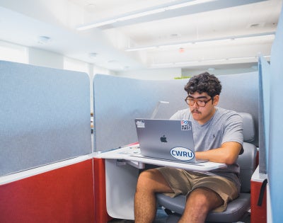Student works on a laptop in a booth at Kelvin Smith Library.