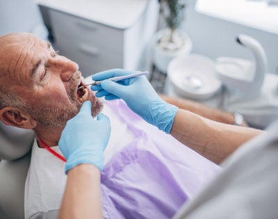 Photo of man being examined in a dental chair.