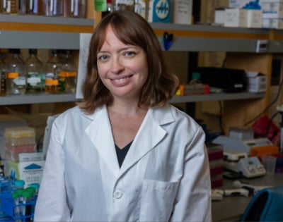 Leah Gates wearing a white coat in a lab setting