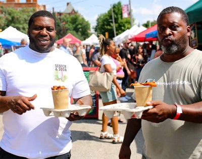 Two men pose for a photo at the Garlic Festival with a cup of food each