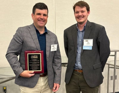 Christopher Wirth takes a group photo holding L.E. Scriven Young Investigator Award statue