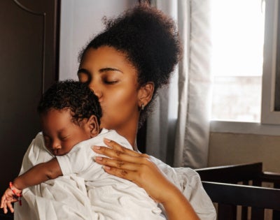 A mother holds a small baby wearing white