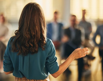 Back view of a woman speaking to a group