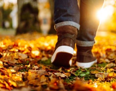 Close up of an unidentified person walking on autumn leaves