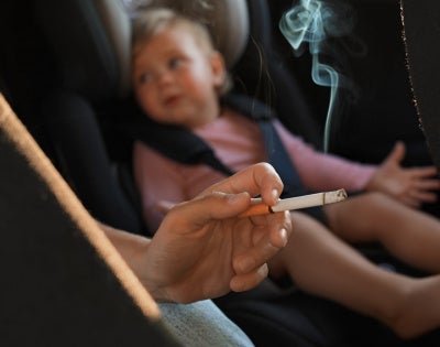 Image of a human smoking next to a baby