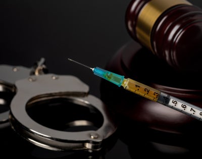 Image of a gavel, handcuffs and syringe