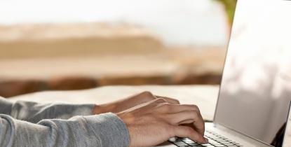 Close up photo of hands typing on laptop