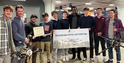 Members of VTOL gather for a photo with their team banner