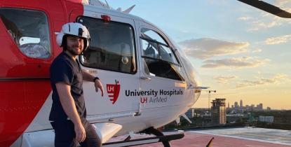 CRNA student Robert Sharkey stands in front of a medical helicopter on a rooftop.