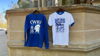 Photo showing two limited-edition Hudson Relays merch items—a t-shirt and a sweatshirt—hanging from the portico at Adelbert Hall