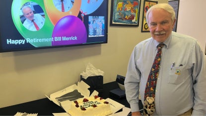 Bill Merrick posing with a cake at his retirement party