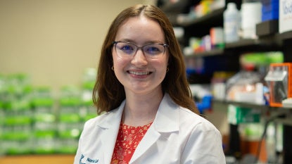 Photo of Chloe Meyer wearing a white coat in a lab setting