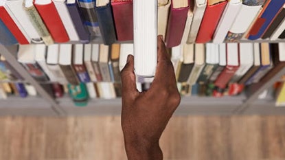 A hand takes a book off a shelf.