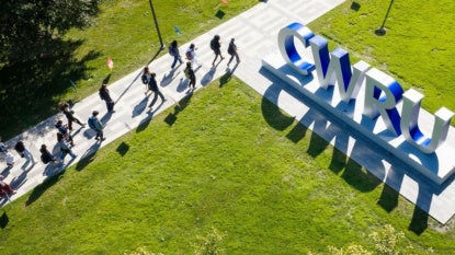 Aerial view of students walking on campus near big CWRU-lettered sign. 