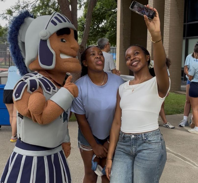 Mascot Spartie poses for a selfie with two CWRU first-year students outside on move-in day.