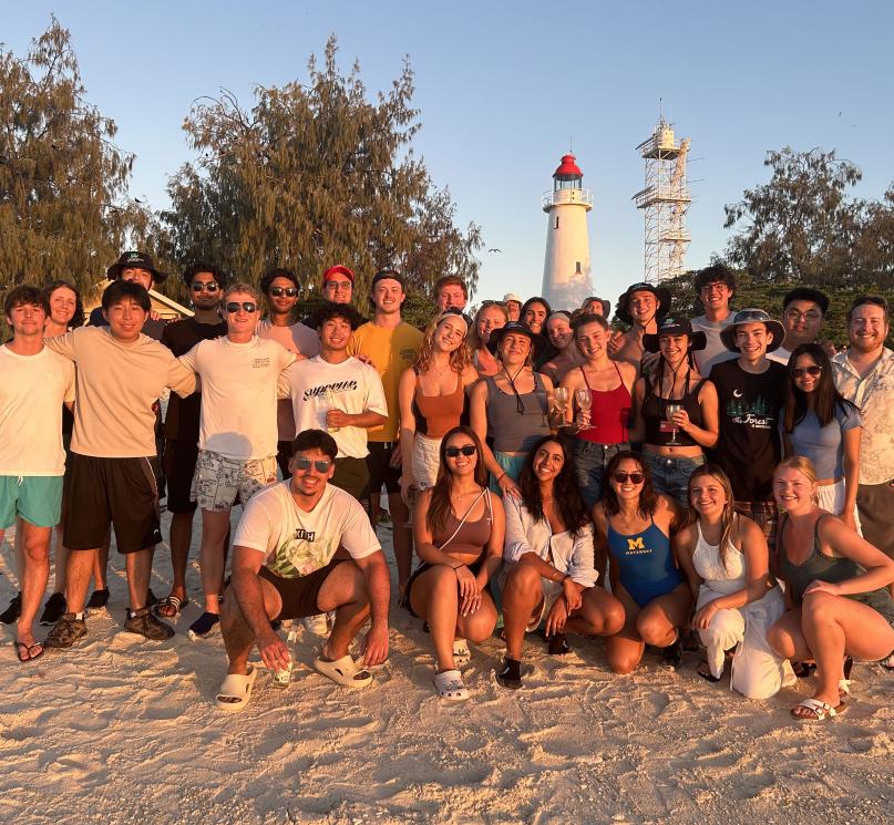 A large group of students posing on a beach.