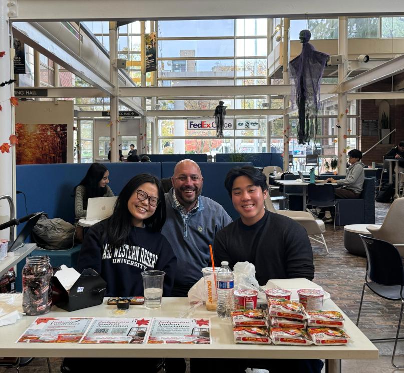 Three people posing at a table in Thwing Student Center.