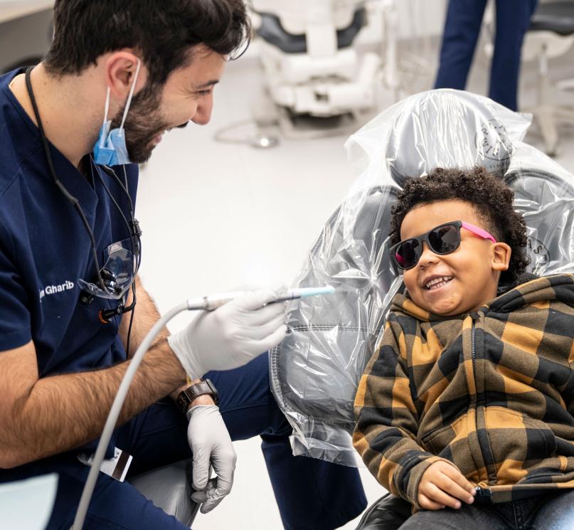 A dental student providing care to a smiling child.