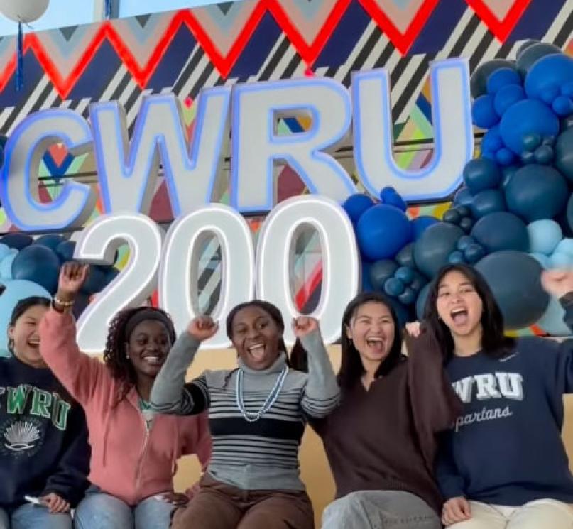 A group of students cheering in front of letters that read, “CWRU 200.”