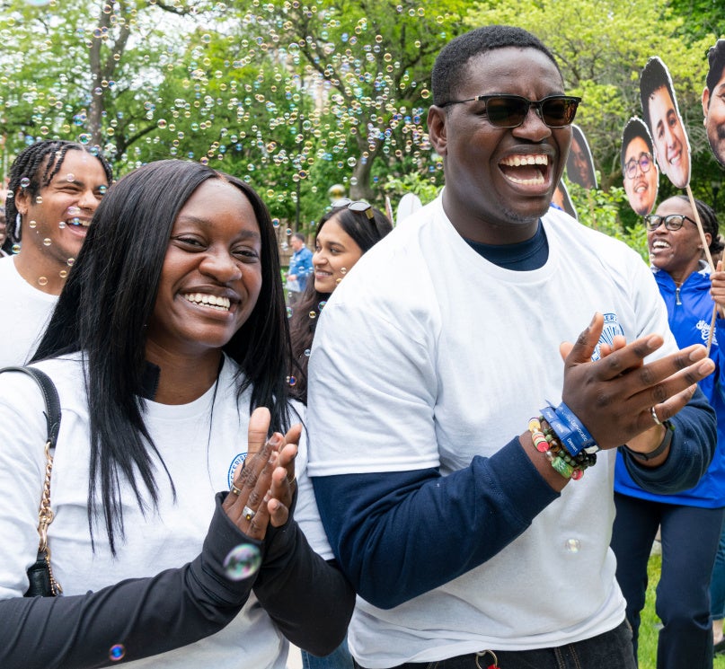 Two students smiling and clapping with bubbles floating behind them on Case Quad