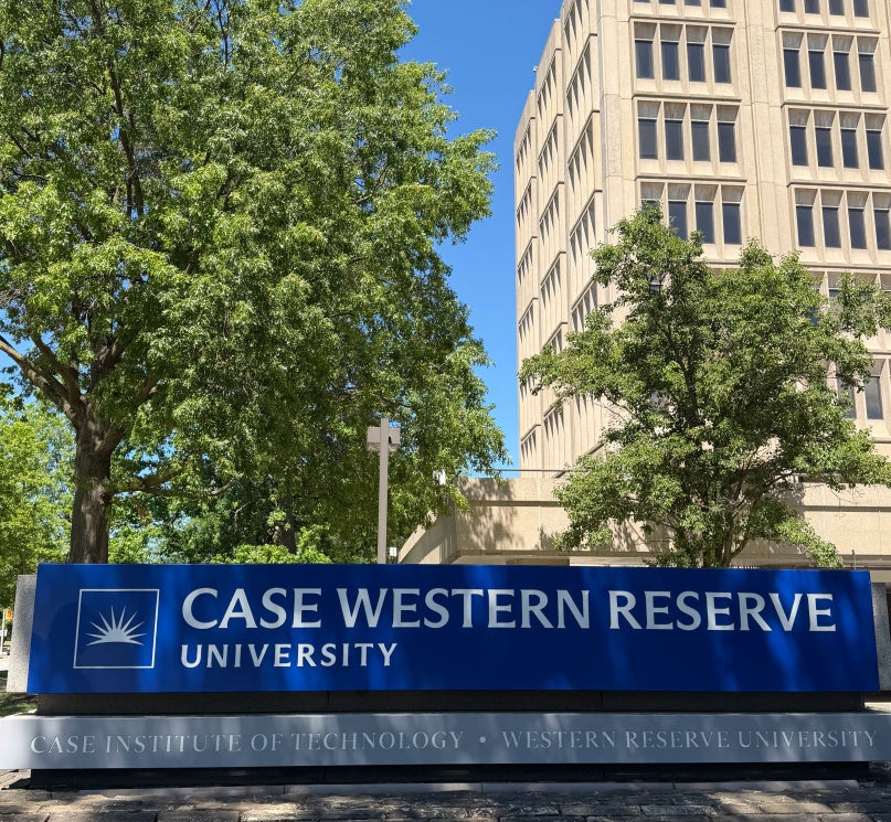 A blue and grey sign reading "Case Western Reserve University" above "Case Institute of Technology • Western Reserve University," with trees and Crawford Hall in the background.