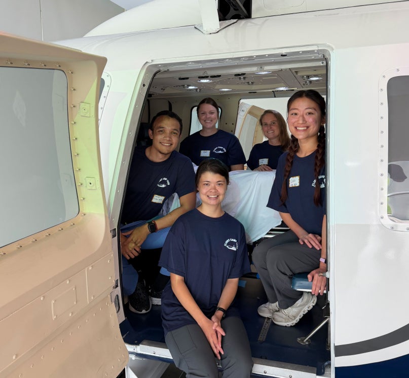 Five nurses pose in Frances Payne Bolton School of Nursing’s helicopter flight simulator.