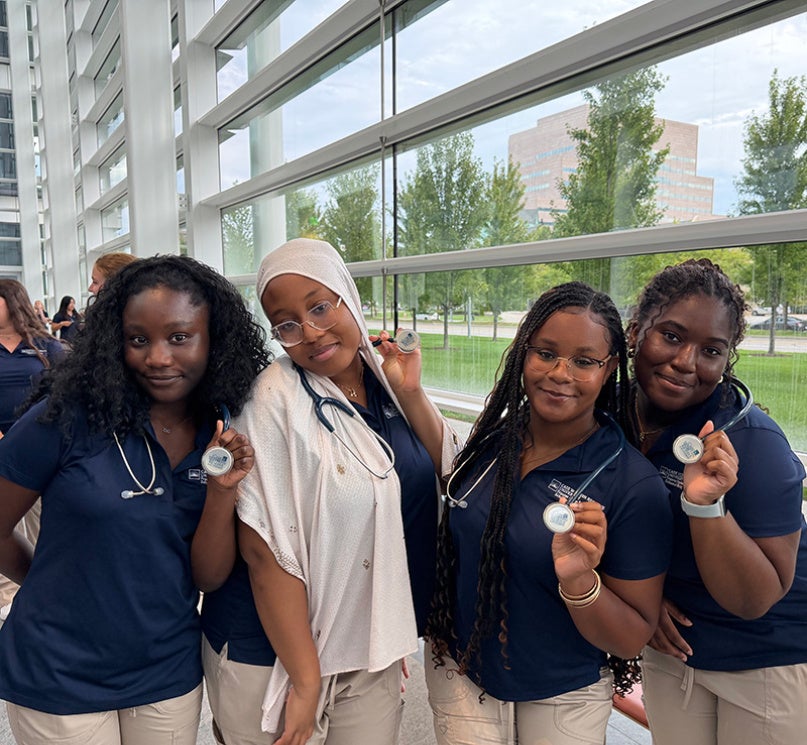 A group of four nursing students posing with their stethoscopes.
