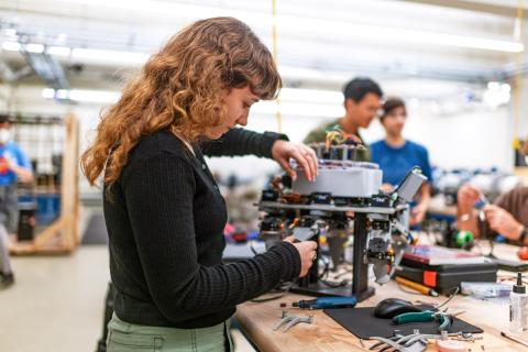 A photo of a student student working on a robotic device.