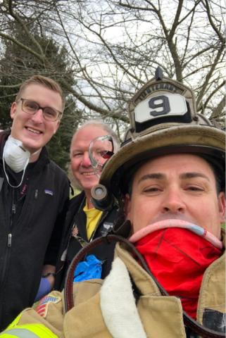 Tanner Purnhagen and a colleague take a selfie with a firefighter with trees behind them.