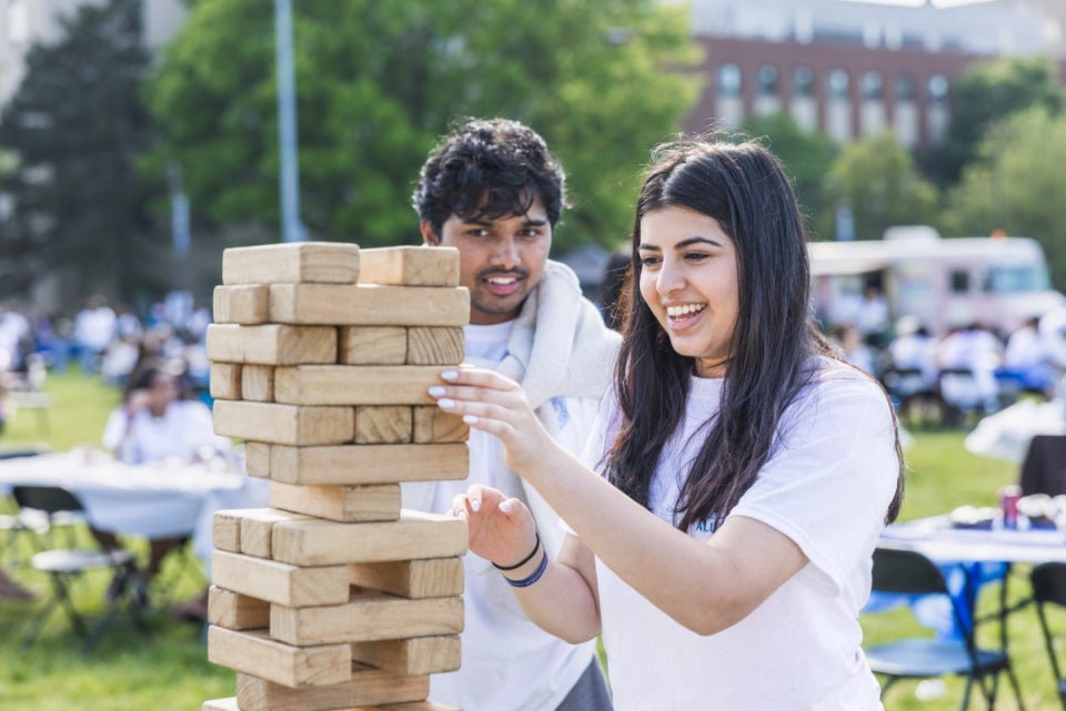 Two students play a large game of jenga outside
