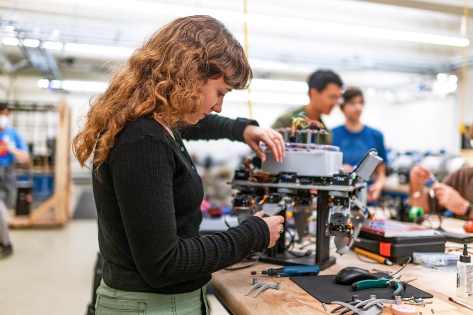 A photo of a student student working on a robotic device.