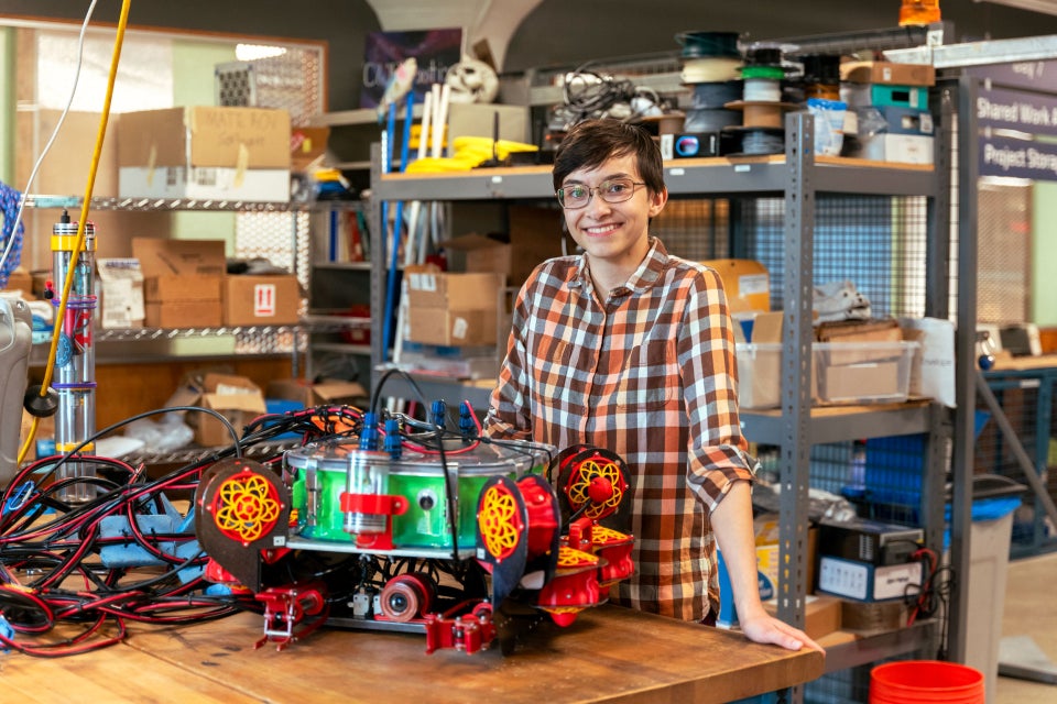 A photo of Amitan Bar-Evan posing with a colorful, intricate robotic device.