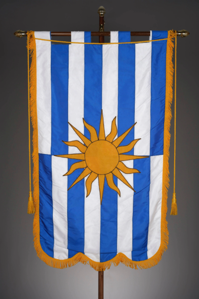 Banner on a pole with blue and white stripes with a gold fringe around it