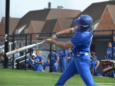 Karen Potts hits a ball while batting at a softball game. 