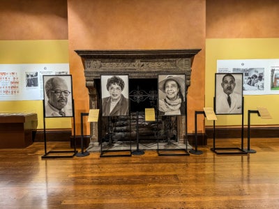 A series of poster-sized photos are displayed in front of an ornate fireplace.