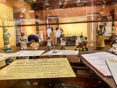 Historic papers and figurines of Black nurses are displayed in a glass case.