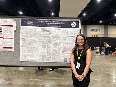 Photo of Kit Shiells in front of her research poster at NCUR