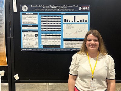 Paris Martin poses for a photo with her NCUR research poster