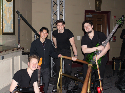Henry Herrera posing with a guitar and 3 bandmates