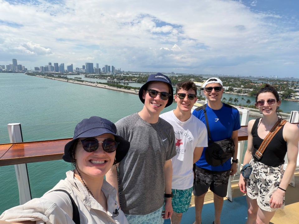 Peter Chin smiling with friends on a balcony overlooking the beach
