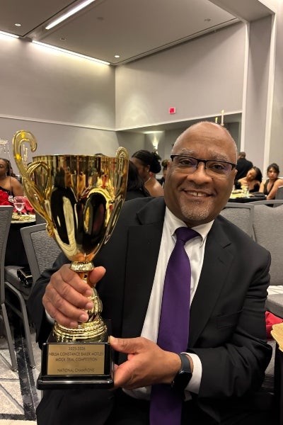 Russ Tye holding the trophy for the 2025-2026 BLSA Mock Trial National Championship