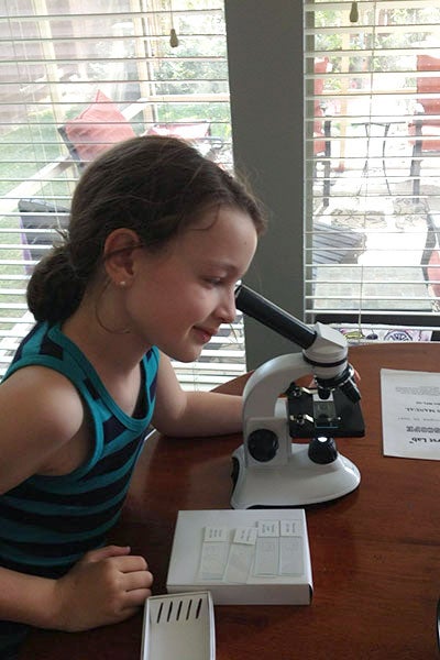 Photo a childhood Chloe Meyer peering into a microscope