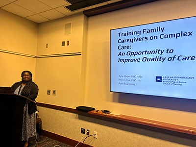 Photo of Ruth Boampong at a podium as she presents about her research on aging
