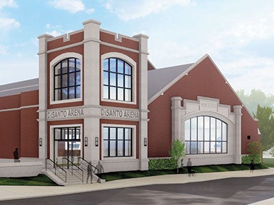 Red-brick building labeled "DiSanto Arena" features large arched windows, white stone accents, and a modern design. Trees and path surround it.