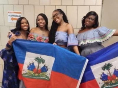Rickelldy Joachim (far right) and a group of peers pose with large Haitian flags. 