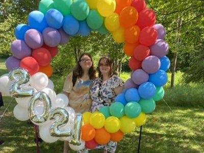 Alyssa Morgan and her wife Katie take a picture behind LGBTQ+ pride-themed balloons. 